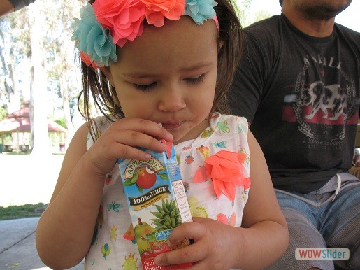 a girl is enjoying her juice at park day